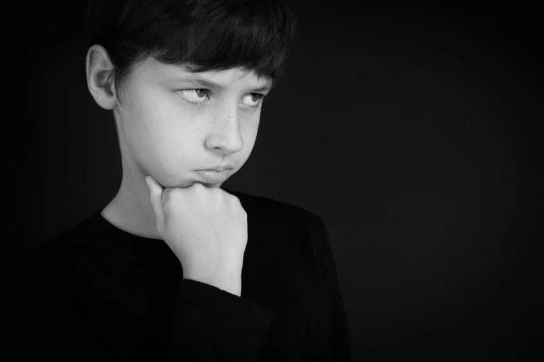 a black and white pograph of a boy with his hand under his chin