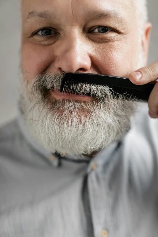 an older man holding a hair comb to his face