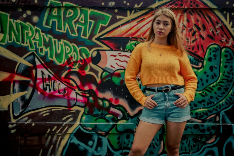 a young lady stands in front of graffiti