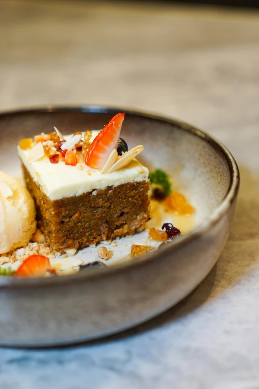 a dessert dish of cake, nuts and fruit sits on a plate