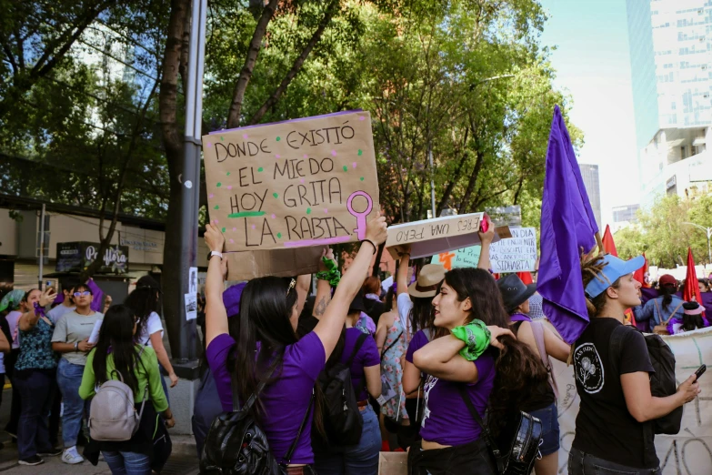 some people protesting on a sidewalk holding up signs