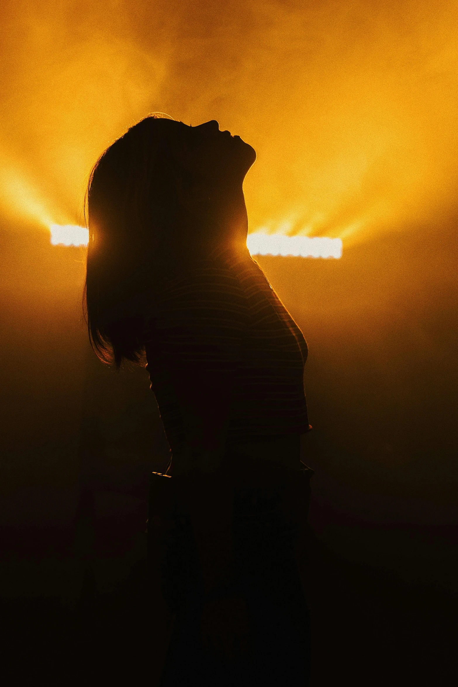 a woman is seen in the light while she's standing against a dark background