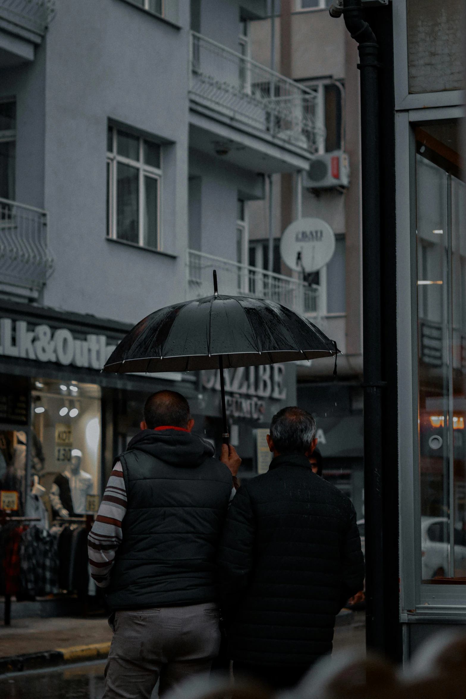 a couple holding an umbrella while walking down the street