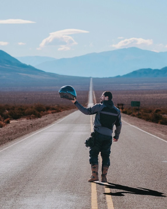 the person is walking down the road with his helmet on