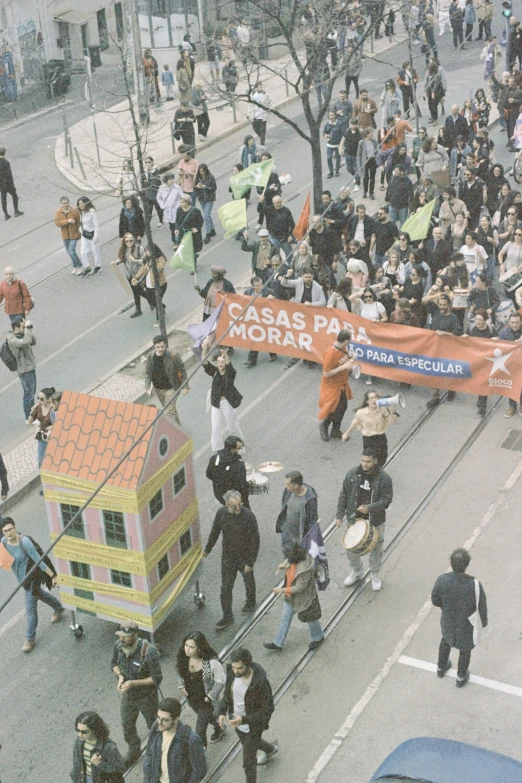 people marching down a street with a giant building