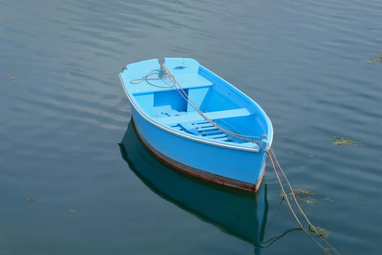 small blue boat on calm surface of still water