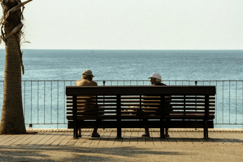 two people sit on a bench overlooking the water