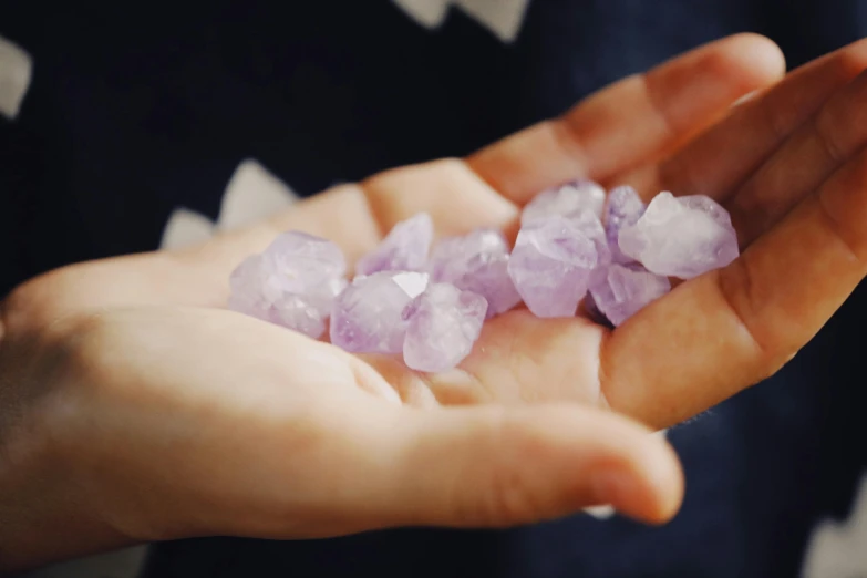 this is a person holding some small pink crystals