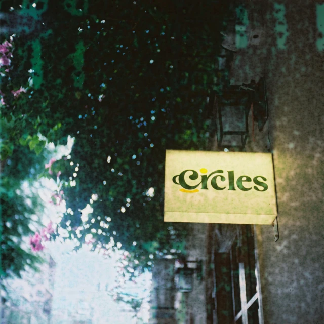 the business sign is lit up under some trees