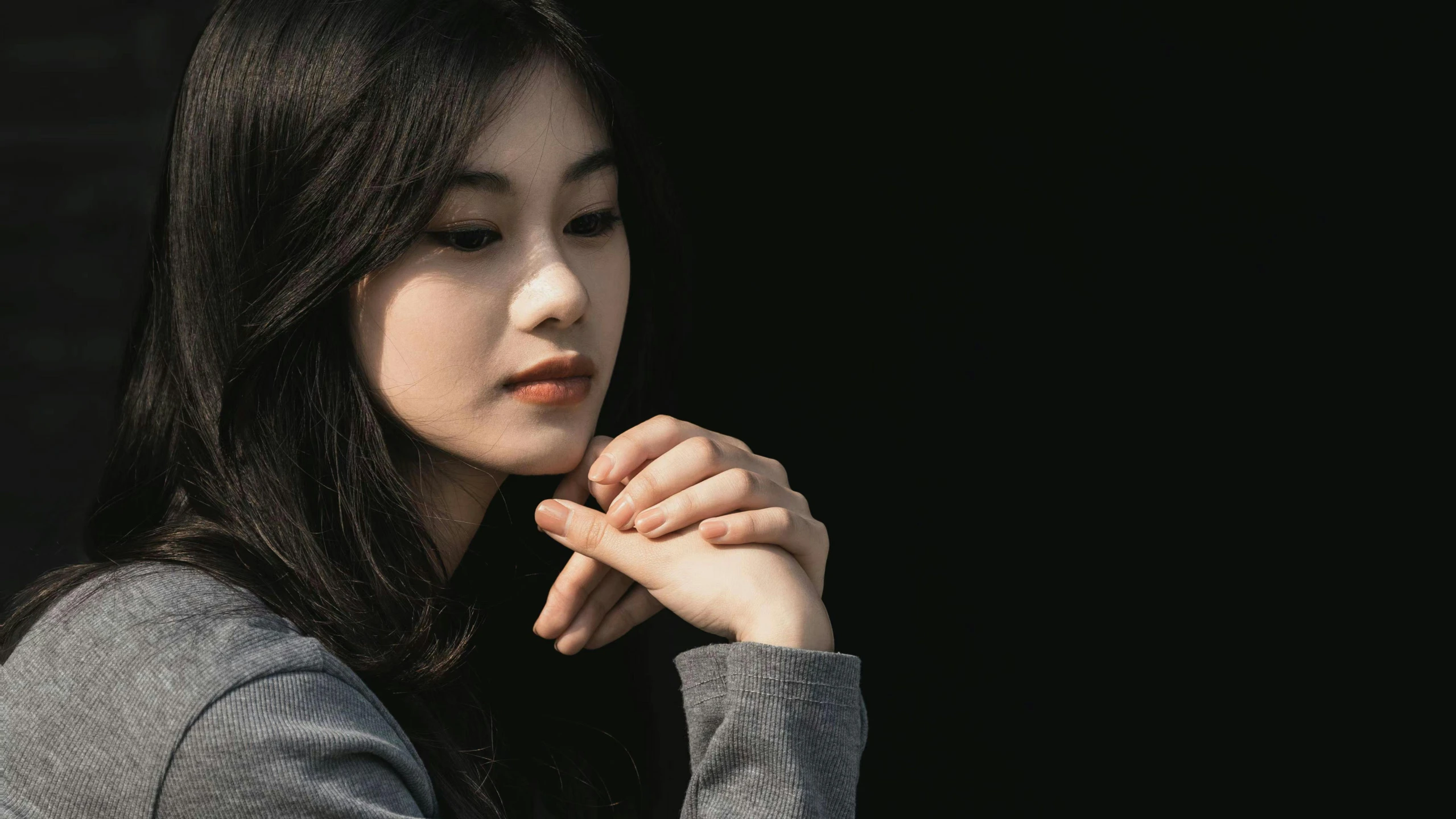 an asian woman wearing gray sweater holding her hands in front of her