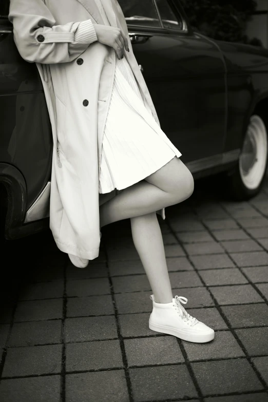 a woman leans against a car, her hands on the tire