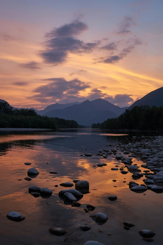 rock on shore with water in foreground at twilight