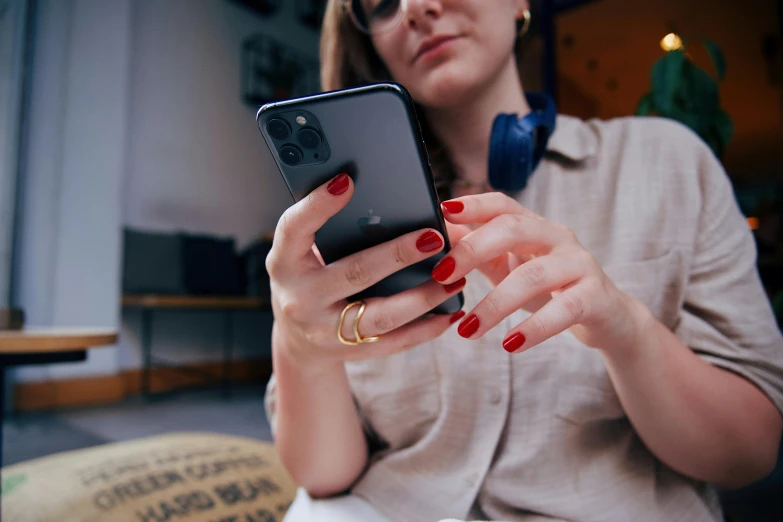 woman with bright nail polish is looking at her cellphone