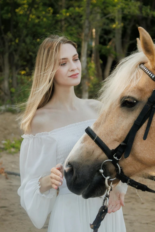 woman wearing white dress holding reins on a horse