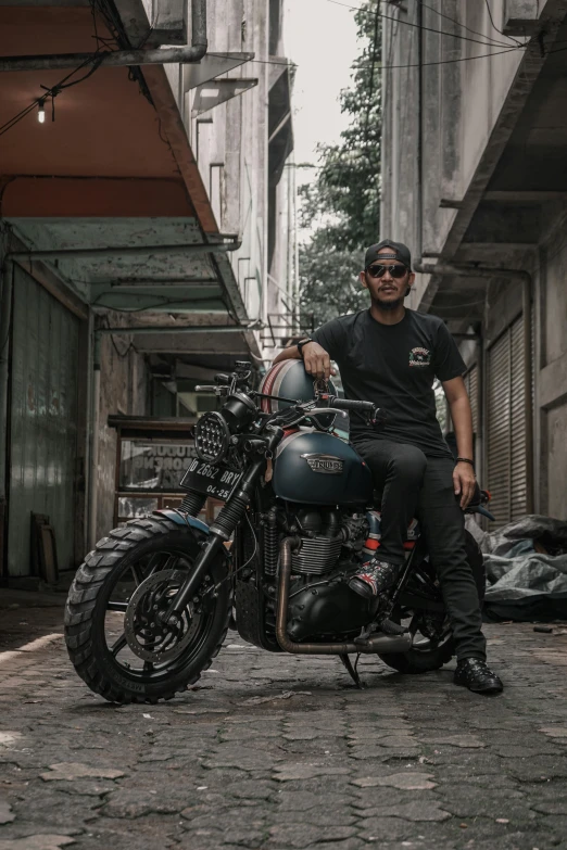 a man wearing sunglasses and a black shirt sits on his motorcycle