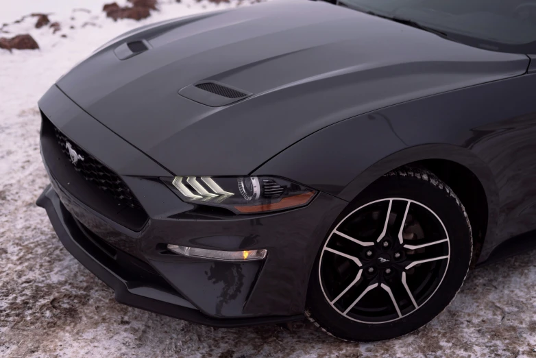 an all black mustang is parked in the snow