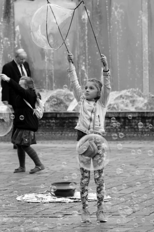 a small child holding onto two clear umbrellas