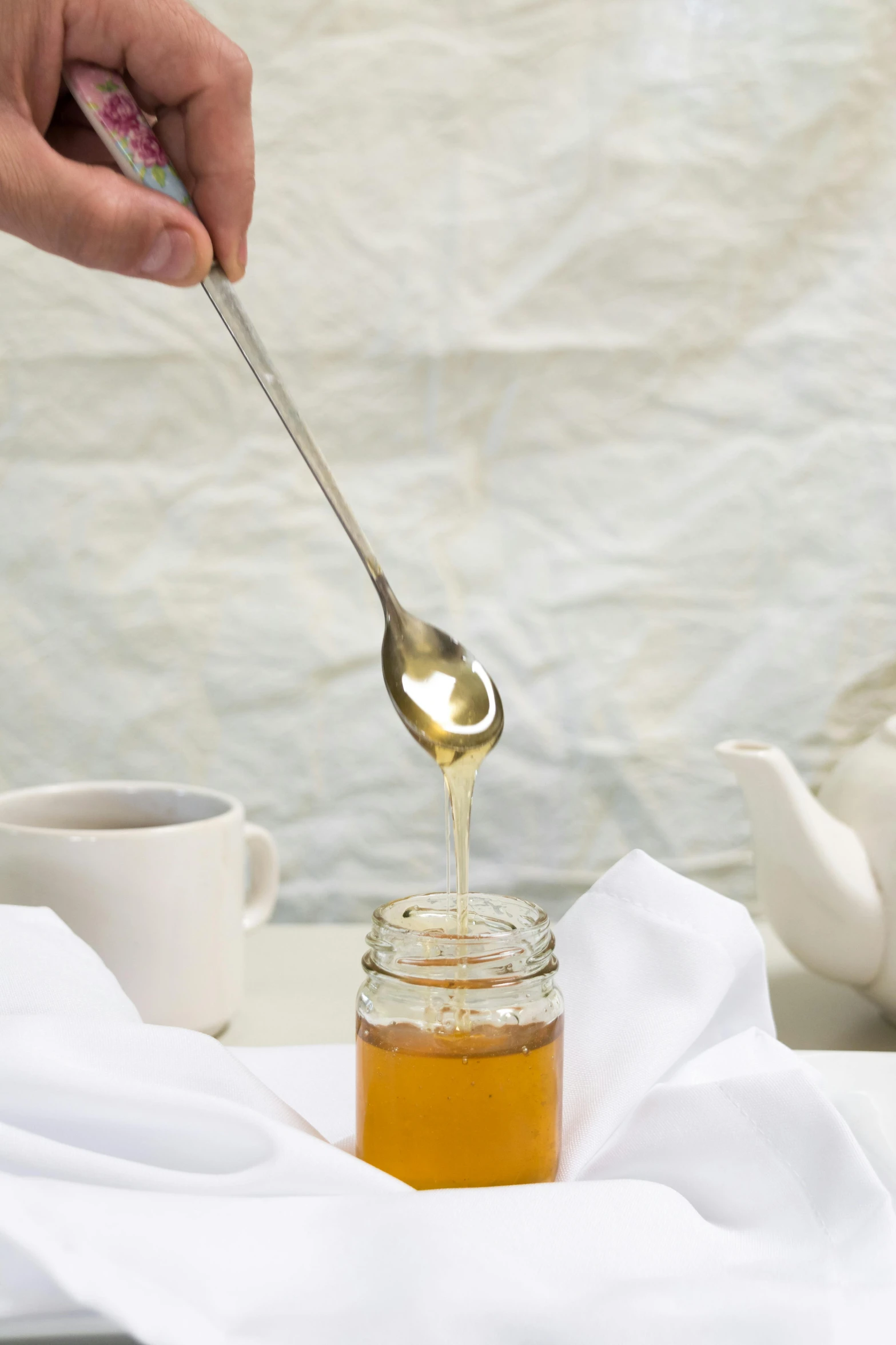 a spoon with some honey on it sitting in a jar