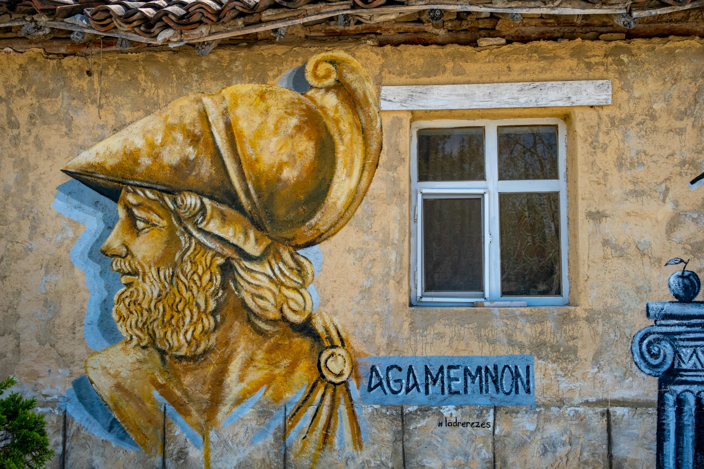 a painting on the side of a building of an old man with a hat and a yellow robe