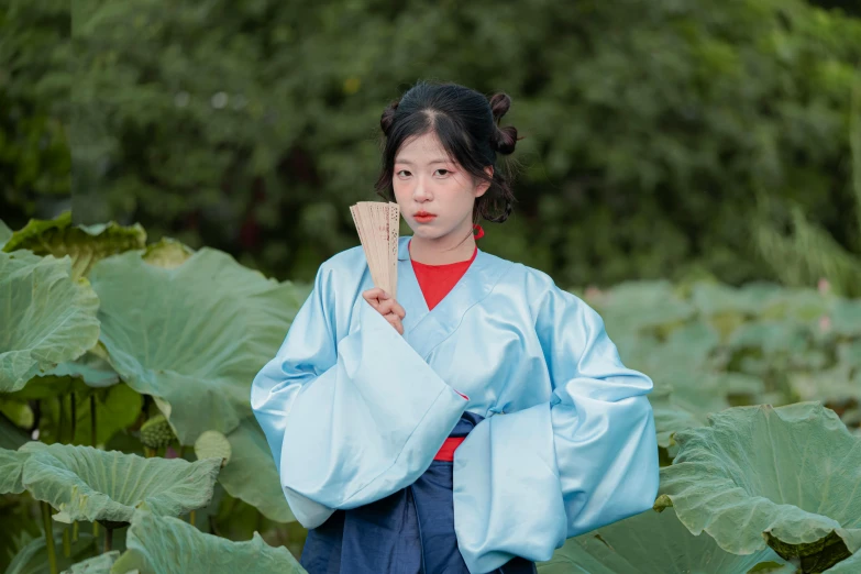 an asian woman in a blue robe holding a piece of wood