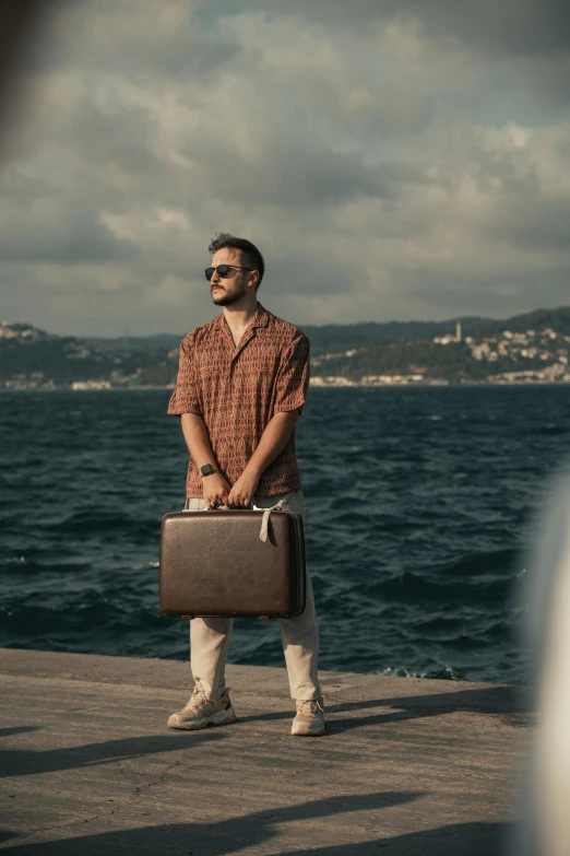 a man holding a brief case looking at the water