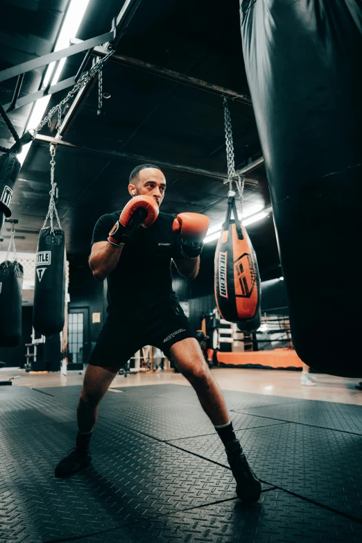 a man is wearing all black in a gym punching