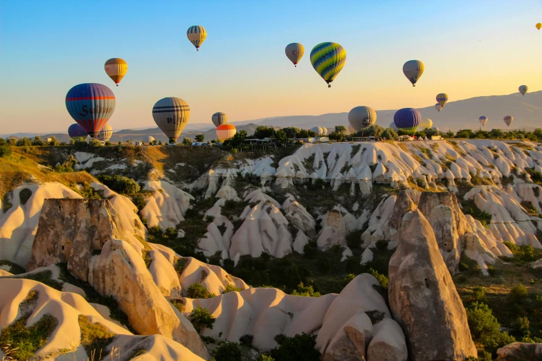  air balloons flying over a rocky landscape at dusk