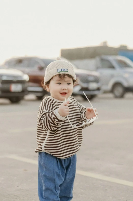 a little boy standing in a parking lot with a controller in his hand