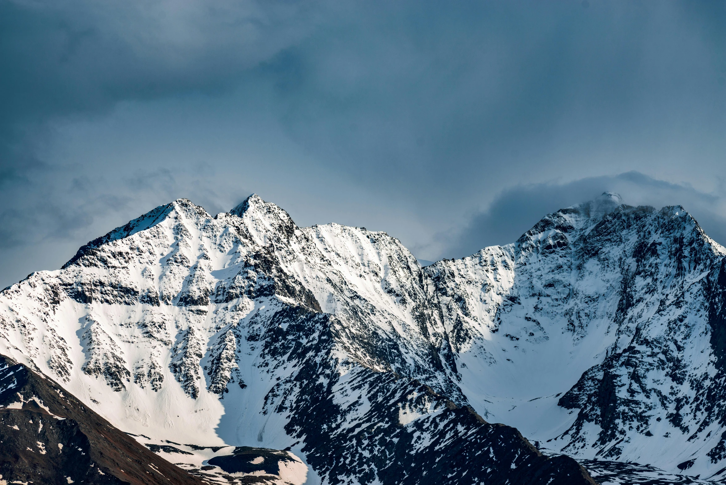 a very tall snow covered mountain under a cloudy sky