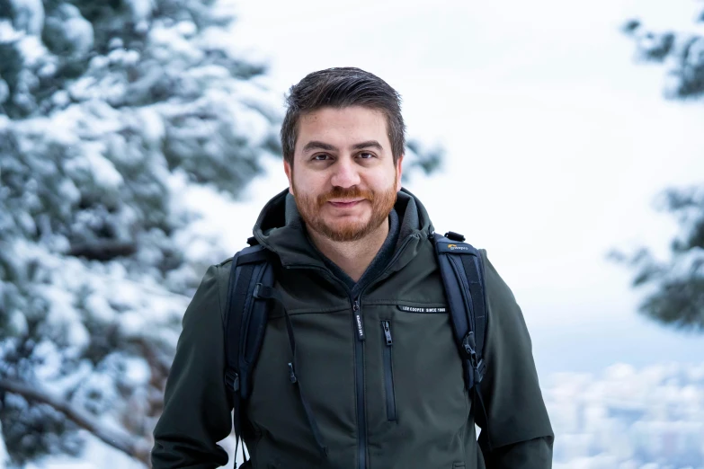 a man wearing a backpack standing in the snow