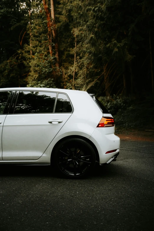 a white car parked next to a forest