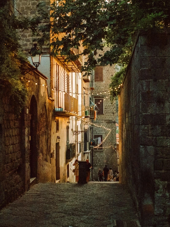 a narrow street has a tree and stone buildings