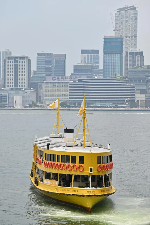 yellow ferry boat moving on water with city in background