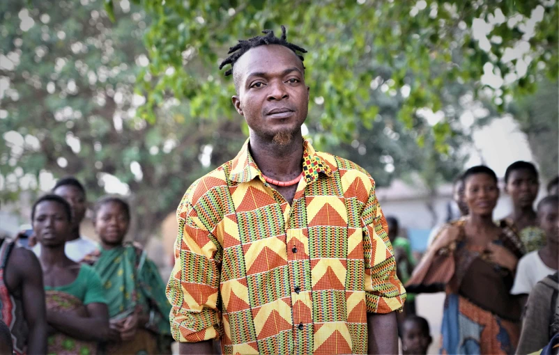 a man wearing a bright shirt and looking to his right with an audience behind him