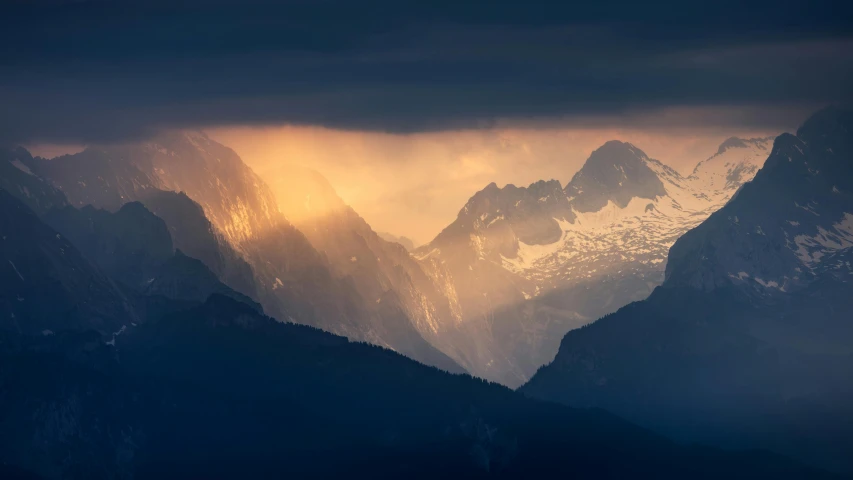 a couple of mountain tops with a cloudy sky behind them