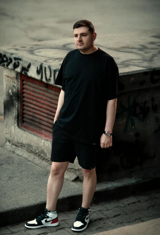 a man in black shorts standing by some graffiti on a building