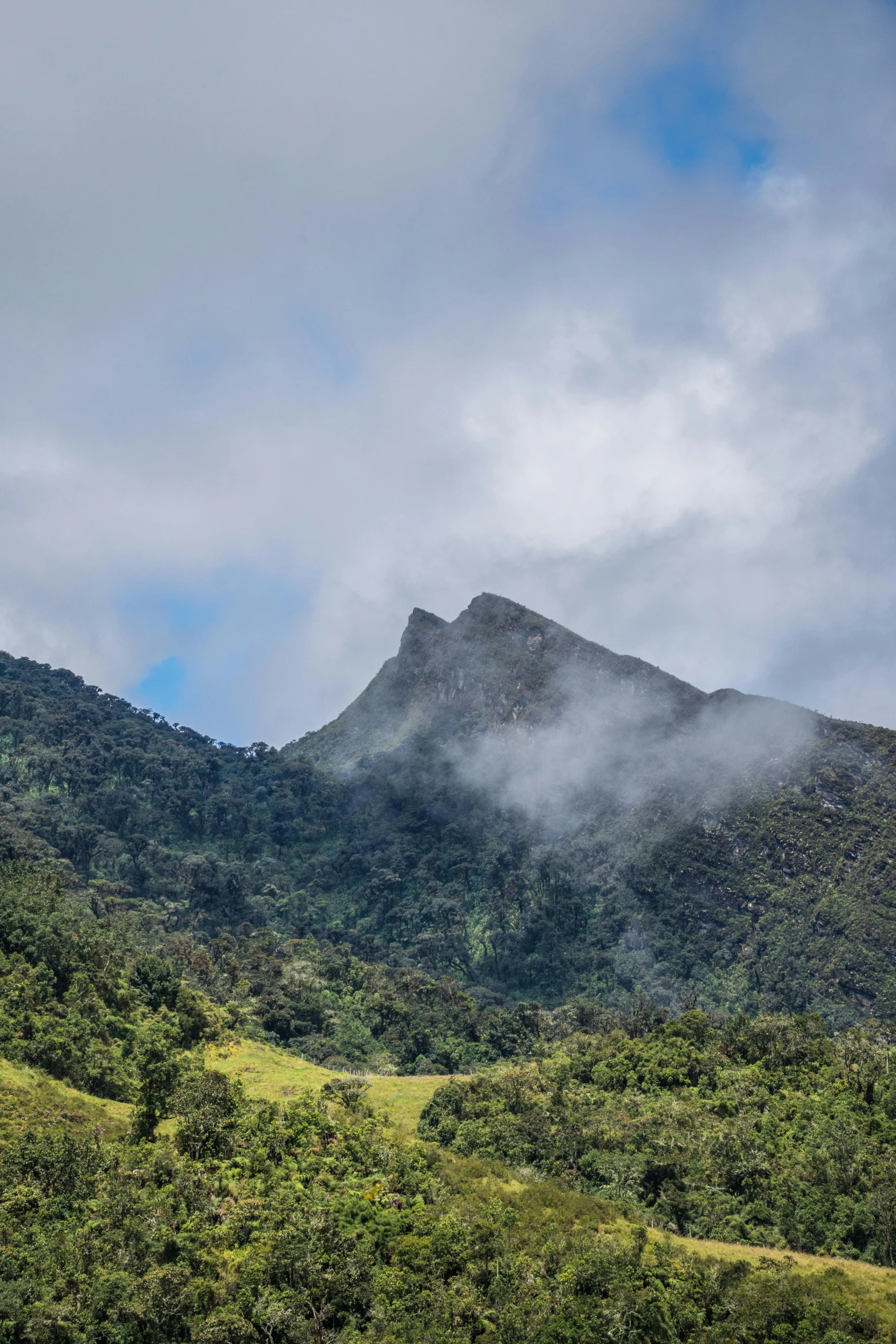 a grassy field on top of a hill under a cloudy sky