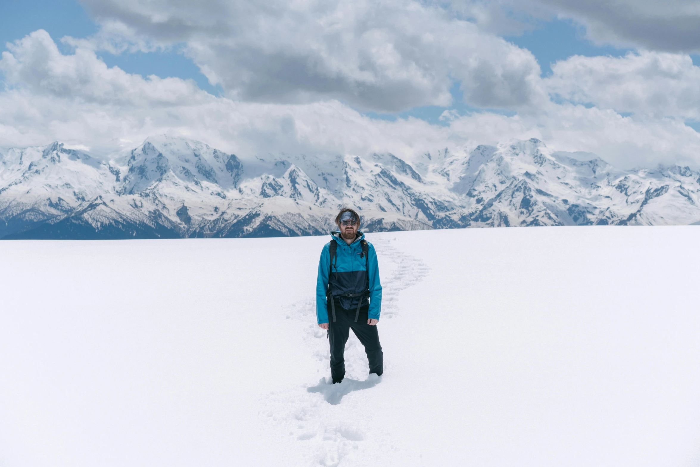 a woman in a blue jacket standing on top of snow covered ground