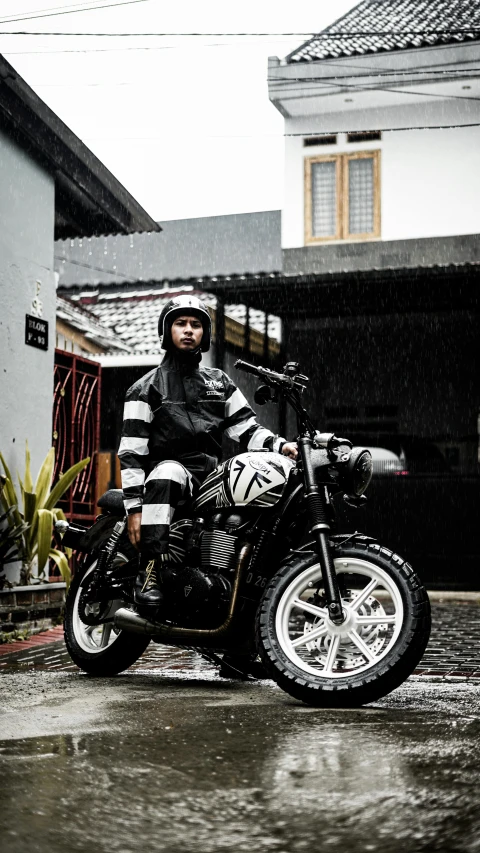 a man sitting on his motorcycle outside in the rain