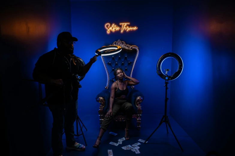 a man standing behind a blue throne next to a camera