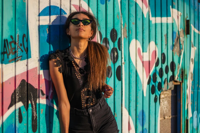 a woman poses in front of an industrial wall