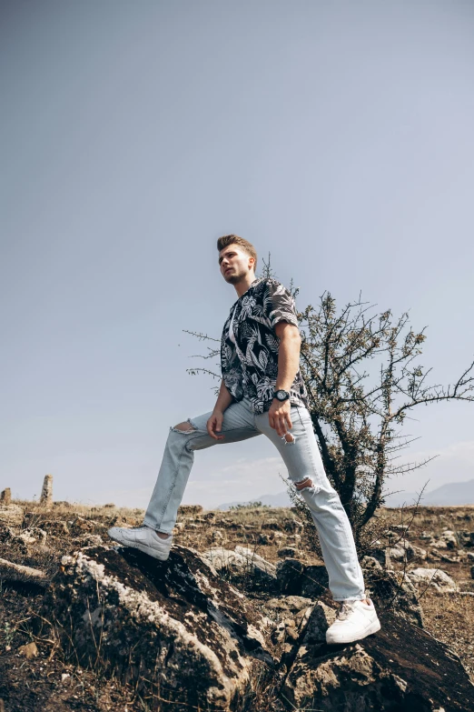 the young man in the shirt is posing on a rock