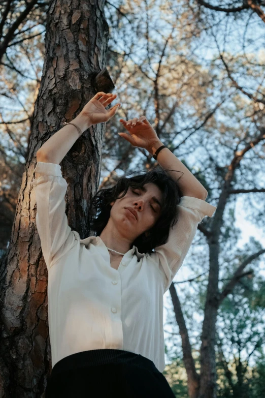 the young woman is reaching up into the trees