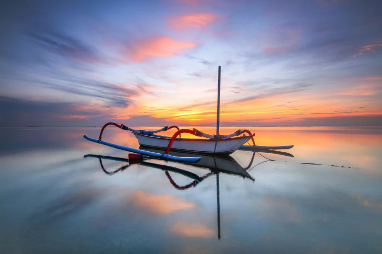 a colorful sunset reflecting a boat with red and blue details