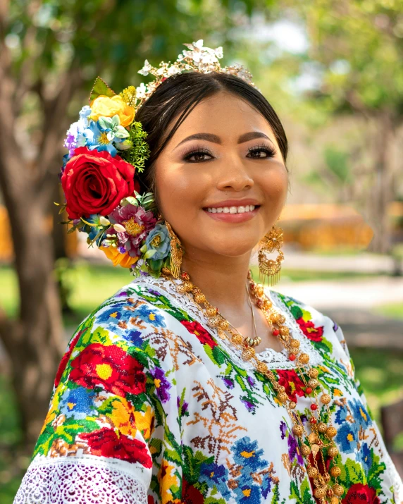 a woman in traditional dress smiles and holds up flowers in her hair