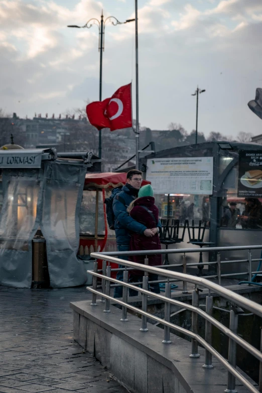 two people with red umbrellas standing on sidewalk