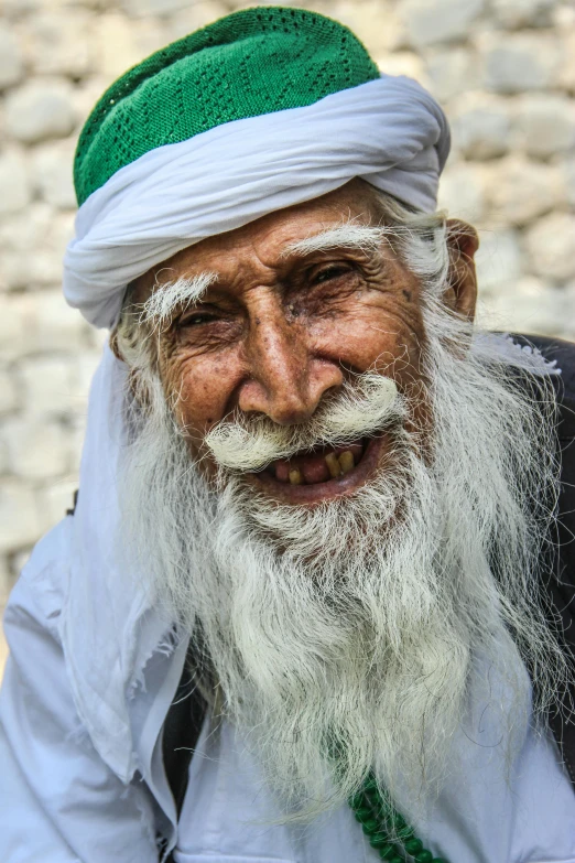 an elderly man wearing a long beard and a green hat