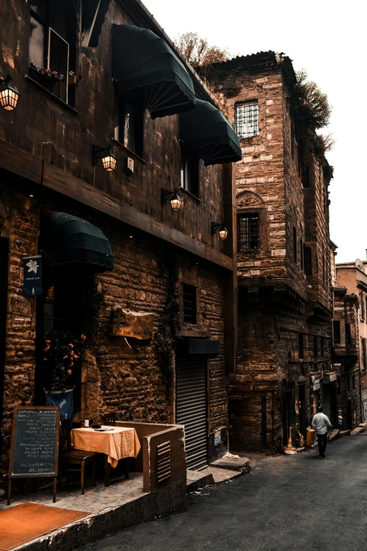 two people walk down an empty street past an old brick building