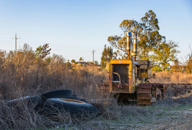 a cat tractor parked in a field next to an old tire