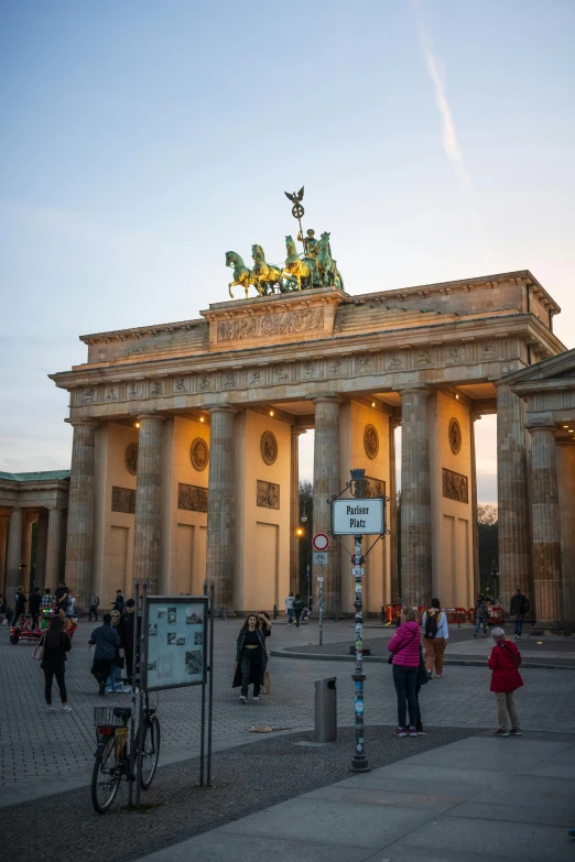 people walking around outside a very tall arch